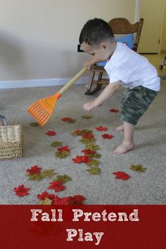 a young boy is playing with leaves on the floor while holding a broom in his hand