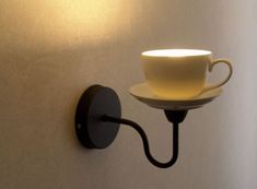 a coffee cup on a saucer mounted to a wall with a light bulb plugged in