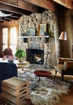 a living room filled with furniture and a fire place next to a stone fireplace covered in logs