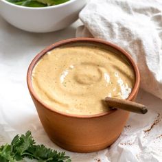 a brown bowl filled with soup next to a white bowl full of lettuce