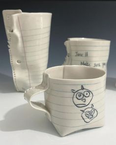 three coffee cups with drawings on them sitting next to each other