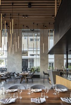 an empty restaurant with wooden tables and chairs, along with hanging lights above the dining area