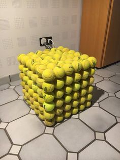 a bunch of tennis balls stacked on top of each other in the middle of a room