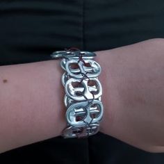 a close up of a person's arm wearing a silver bracelet with links on it