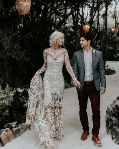 a man and woman walking down a path holding hands