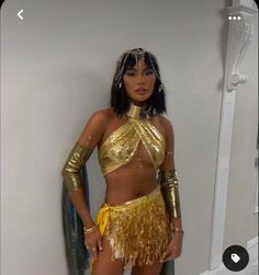 a woman in a gold outfit standing next to a mirror with her hands on her hips