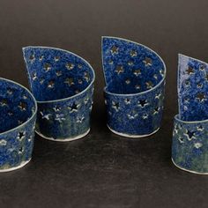 four blue cups with stars on them sitting next to each other in front of a black background