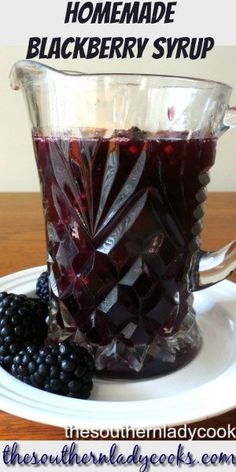 a glass pitcher filled with blackberry syrup on top of a white plate