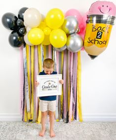 a young boy holding up a sign in front of balloons