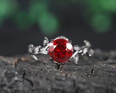 a red ring sitting on top of a piece of wood next to a green leaf