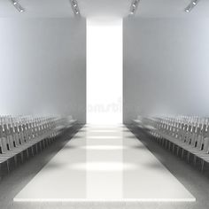 an empty white room with rows of chairs in front of the door and light at the end