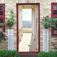 an open door leading to a house with red shutters and flowers on the outside