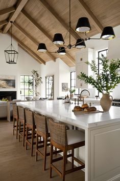 a large kitchen with white counter tops and wooden ceiling lights hanging from the rafters