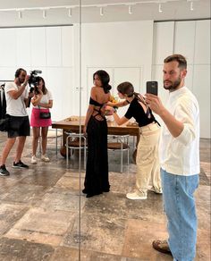 a group of people taking pictures with their cell phones in an empty room while others take photos