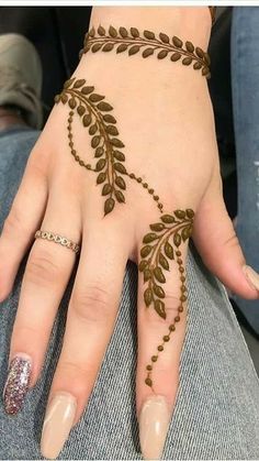 a woman's hand with hennap on it and two fingers that are decorated with leaves