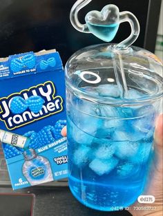 someone is holding up a blue drink in front of a box of jelly rancher