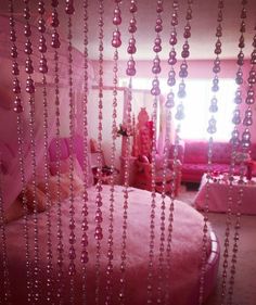 a pink bedroom with beads hanging from the ceiling