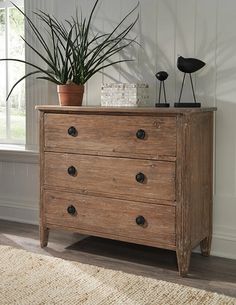 a wooden dresser with two plants on top