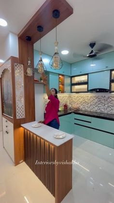 a woman is standing in the middle of a kitchen with blue cabinets and white countertops