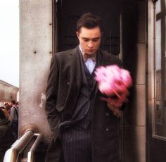 a man in a suit and tie holding a pink flower