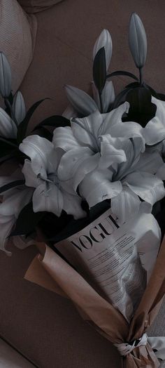 a bouquet of white flowers sitting on top of a couch next to a book and magazine