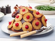 a pineapple upside down cake on a plate with fork and knife next to it