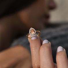 a close up of a person holding a ring with a diamond on it's middle finger