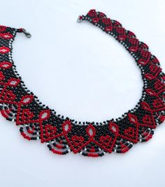 a red and black beaded necklace on a white surface