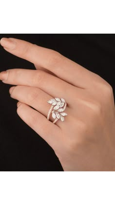 a woman's hand wearing a ring with leaves on it and diamonds in the middle