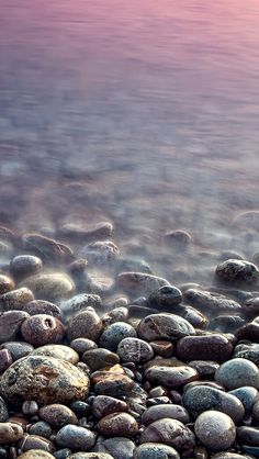 some rocks and water at the beach with pink skies in the background, as seen from above