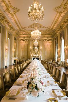 the long table is set with place settings and flowers on it, along with gold trimmings