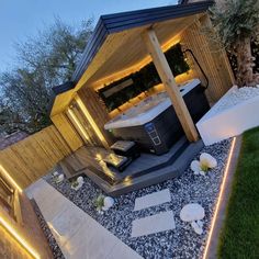 an outdoor hot tub in the middle of a garden with lights on it's sides