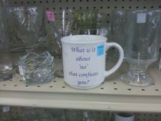 a white coffee mug sitting on top of a shelf next to glass cups and glasses