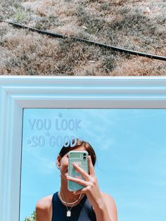 a woman taking a selfie in front of a mirror with the words you look $ 50 good written on it