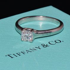 a diamond ring sitting on top of a blue box with the word tiffany & co written below it