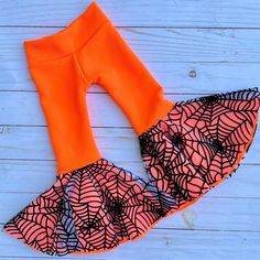 an orange and black skirt with spider webs on the bottom is laying on a white wooden surface