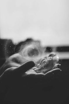 a person holding something in their hand with water droplets on it's palm and blurry window behind them