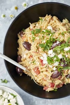 a black bowl filled with pasta and olives