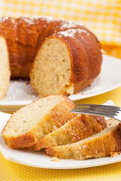 two plates with slices of bread on them and a fork next to one plate that has a loaf of bread on it