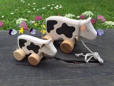 a wooden toy cow pulling a rope with flowers in the background