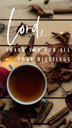 a cup of tea sitting on top of a wooden table next to leaves and candles