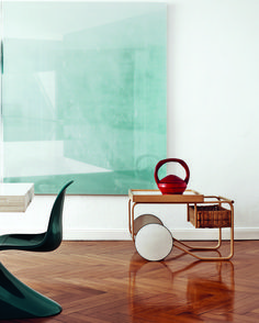 a chair sitting on top of a wooden floor next to a table with a vase