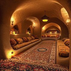 a living room filled with lots of couches next to a rug and lights on the wall