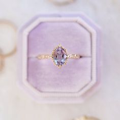 an engagement ring with a large blue stone in it's center sits on top of a purple velvet box