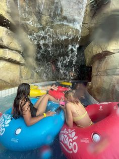 two women in bikinis are riding on rafts at the water park while another woman watches