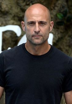 a bald man in a black shirt posing for the camera