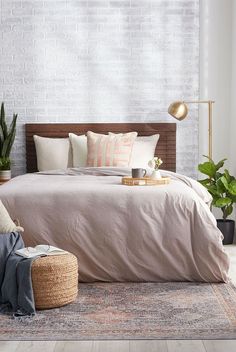 a bedroom with white brick walls and wooden bed frame, pink linens on the bed