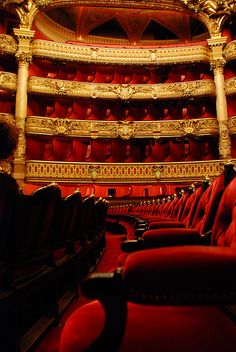 an empty theater with red seats and gold trim