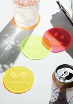 three smiley face coasters sitting on top of a table next to a can of soda