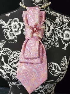 This Pink and Purple Paisley Necktie Necklace is made with a (Barry Wang) woven silk tie, and features a Pink Starfish Rhinestone Brooch strung on your choice of an adjustable Rosary Chain Ribbon Tie Pearl Necklace or an adjustable Elastic Band. The soft, comfortable fabric sits perfectly on any size chest, while the adjustable necklace feature allows you to customize the fit to your liking. Measuring at a versatile length, this necktie necklace is designed to be a one-size-fits-all. View all Wo Luxury Silk Women's Neckwear, Elegant Adjustable Ribbon Neckwear, Pink Adjustable Costume Jewelry Necklace, Elegant Semi-formal Neckwear With Paisley Print, Adjustable Pink Ties For Business, Necktie Necklace, Pink Starfish, Women Necktie, Women Ties